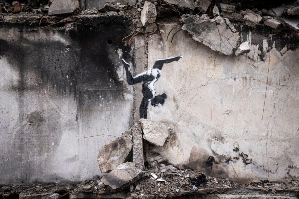 Murale di Banksy che raffigura una ginnasta che pratica un handstand sulle rovine di Borodyanka, Kiev - Kombatnet News