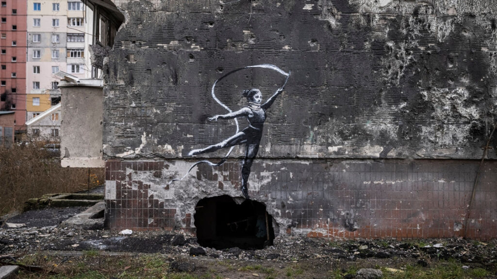 Murale di Banksy che raffigura una ginnasta con il nastro sulle rovine di Borodyanka, Kiev - Kombatnet News